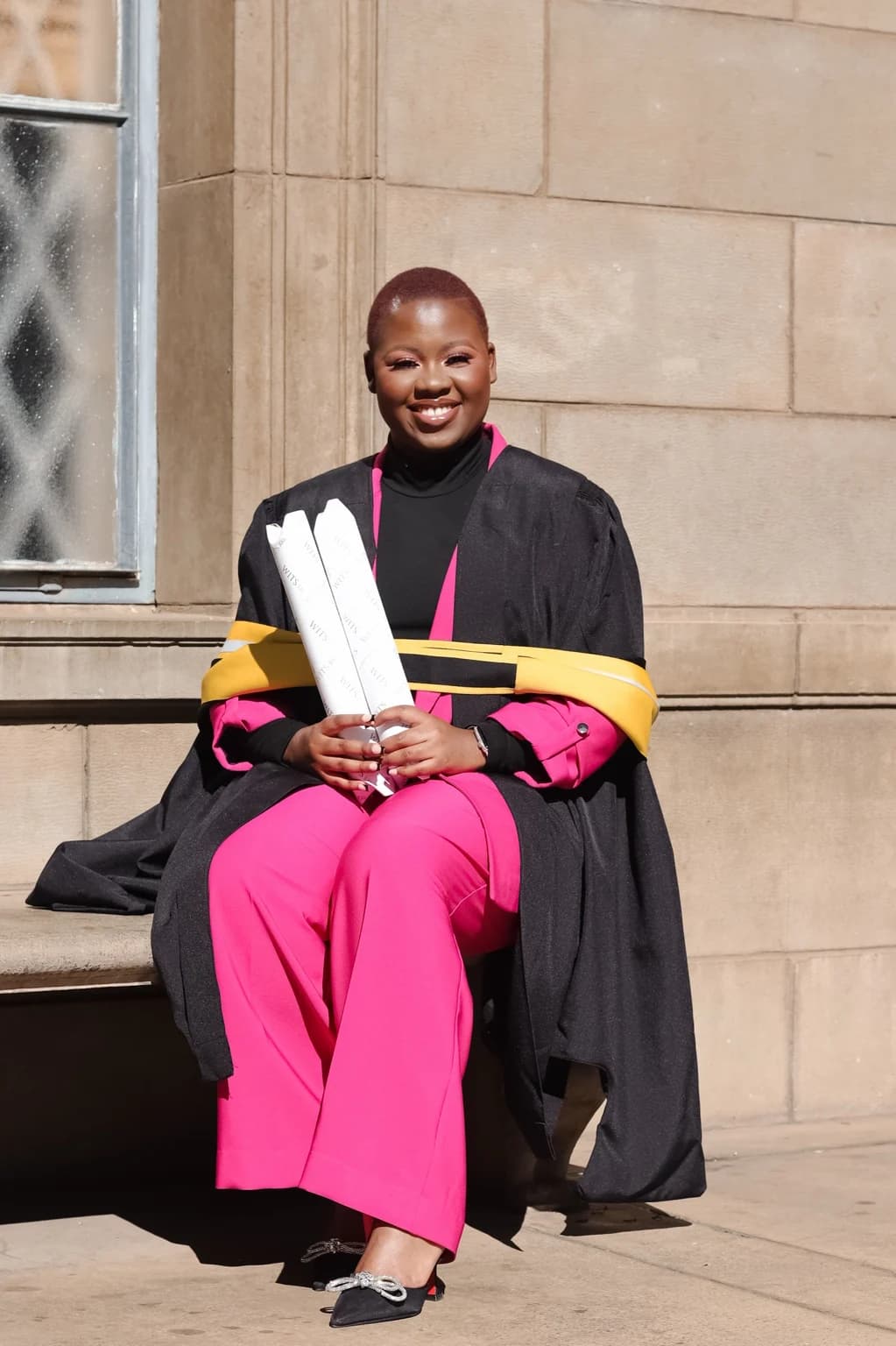 Nqobile Mnisi seated in graduation attire