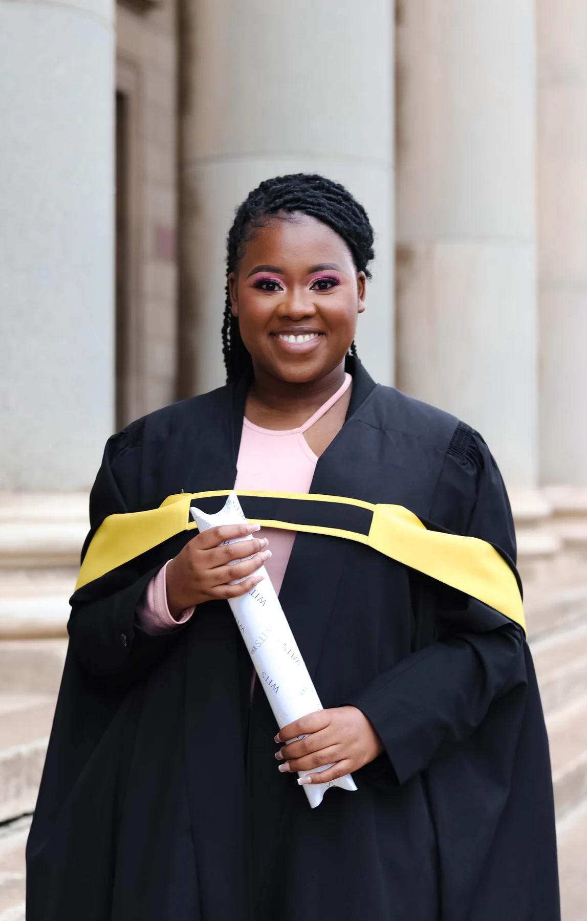 Nqobile Mnisi holding her degree in graduation attire